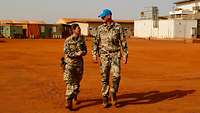 Eine Soldatin und ein Soldat gehen nebeneinander und sprechen 