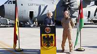 Verteidigungsministerin Lambrecht steht auf dem Flugfeld an einem Pult.