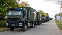 Militärkonvoi mit Sanitätsmaterial Mehrere Lkw beladen mit Containern mit Sanitätskreuz parken hintereinander am Straßenrand.