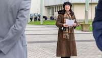 Eine Frau in Winterkleidung mit einem Manuskript