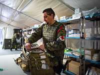 Sanitätsmaterial im Rettungszentrum Role 2 E Ein Soldat mit Sanitätskreuz packt in einem Zelt seinen Notfallrucksack. Hinter ihm stehen Regale mit medizinischem Material.