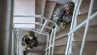 Häuserkampf mit Lasertechnik im Gefechtsübungszentrum Heer Zwei bewaffnete Soldaten mit Treppenhaus eines Gebäudes