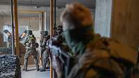 Soldaten trainieren den Häuserkampf im Gefechtsübungszentrum Heer Mehrere bewaffnete Soldaten in einem Gebäude