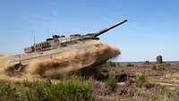 Kampfpanzer Leopard 2 A5 im Gefechtsübungszentrum Heer Ein Kampfpanzer vom Typ Leopard in voller Fahrt im Gelände hebt ab und wirbelt Staub auf.