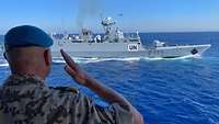 Mit einem militärischen Gruß grüßt ein Soldat ein vorbeifahrendes Schiff