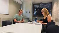 Leah Meyer und Justus Kruse sitzen mit ihren Laptops an einem Tisch in der Tel Aviv University.