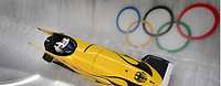 Ein Bob in einer Bobbahn mit Olympischen Ringen