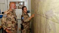 Eine deutsche Soldatin steht mit einem schwedischen Kameraden an einer Lagekarte