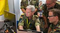 Der Inspekteur CIR sitzt am Computer. Andere Soldaten schauen ihm über die Schulter
