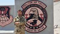 Ein Soldat steht vor einer T-Wall mit dem Wappen der Coalition Air Forces