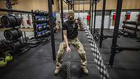 Ein Soldat trainiert mit einem Seil in einer Halle mit Sportgeräten