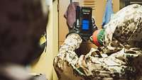 Ein Soldat in einem Schutzanzug hält ein Gerät in den Händen