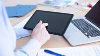 Soldatin arbeitet mit Tablet und Laptop und fotografiert.
