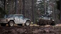 Ein Schützenpanzer Marder und ein HMMWV-Geländewagen im Wald