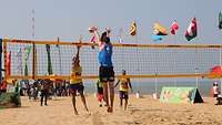 vier Beachvolleyballspieler sprechen auf einem Spielfeld mit einander
