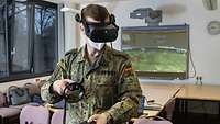 Foto eines Soldaten in Flecktarn der eine VR-Brille trägt und zwei Controller in den Händen hält