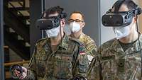 Zwei Soldaten in Flecktarn tragen eine VR-Brille und halten einen Controller in der rechten Hand