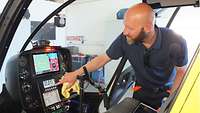 Ein Mann bedient Geräte in einem Hubschraubercockpit.