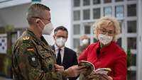 General Bodemann und Verteidigungsministerin Lambrecht schauen gemeinsam in eine Broschüre
