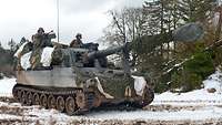 In den Luken einer mächtigen Panzerhaubitze stehen Soldaten.