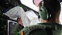 Ein Pilot sitzt mit einer geöffneten Karte im Cockpit