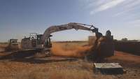 Ein Bagger kippt Sand ab