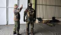 Ein Soldat fotografiert einen Fallschirmspringer in einem Hangar.