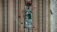 Eine Luftbildaufnahme zeigt Bahnpersonal in orangenen Warnwesten beim Entladen eines Bahnwaggons