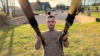 Ein Soldat hält sich rückwärts geneigt an zwei Gurten mit Griffschlaufen fest.