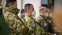 Soldaten verschiedener Nationen lauschen einem Vortrag.