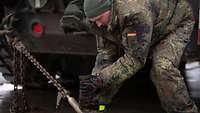 Ein Soldat fixiert mit einer Kette ein Militärfahrzeug auf einem Anhänger