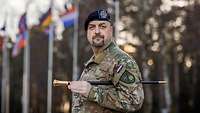 Ein niederländischer Soldat steht vor mehreren Flaggenmasten 