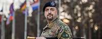 Ein niederländischer Soldat steht vor mehreren Flaggenmasten 