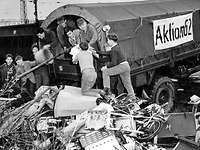 Aufräumarbeiten nach der Sturmflut in Hamburg 1962 Schwarz-Weiß-Aufnahme: Junge Männer und Soldaten laden Schutt von der Ladefläche eines Lkw