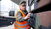 Ein Soldat mit Warnweste entfernt eine Schutzkappe am Kran