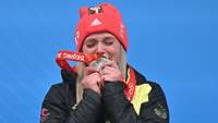 Eine Frau küsst ihre olympische Silbermedaille.