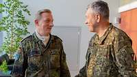 Zwei Soldaten in zwei Flecktarnuniformen stehen in einem Gang und schauen sich freundlich an.