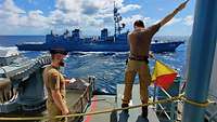 Zwei Soldaten eines Marineschiffs üben ein Manöver mit einem Schiff der japanischen Streitkräfte