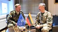 Zwei Soldaten sitzen in einem Raum in Sesseln nebeneinander.