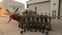 Die ENJJPT-Klasse 22-06 Pilotenschülerinnen und -schüler der Klasse 22-06 posieren in ihren Fliegerkombis für ein Gruppenfoto vor einer T-6.