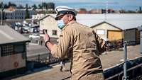 Kommandant eines Militärschiffs beobachtet an Deck ein Anlegemanöver