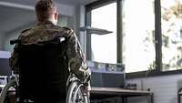 Ein Soldat sitzt in seinem Rollstuhl, den Rücken zur Kamera. Im Hintergrund ist ein Büro zu sehen.