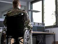 Ein Soldat sitzt in seinem Rollstuhl, den Rücken zur Kamera. Im Hintergrund ist ein Büro zu sehen.