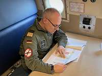 Jan C. Kaack Ein Admiral in olivgrünem Overall sitzt an einem Tisch und liest Papierunterlagen.