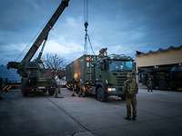 Ein Kran steht neben einem Schwerlasttransporter und hebt einen Container an
