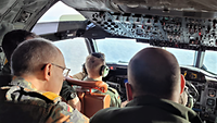 Mehrere Soldaten im Cockpit eines größeren Flugzeugs.