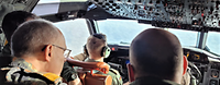 Mehrere Soldaten im Cockpit eines größeren Flugzeugs.