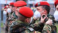 Zwei Soldaten stecken einem dritten Soldaten Dienstgradabzeichen auf die Schultern.