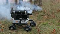 Ein kleiner Roboter auf Rädern im Gelände stösst Rauch aus.