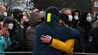 Zwei Menschen in Winterjacken umarmen sich.